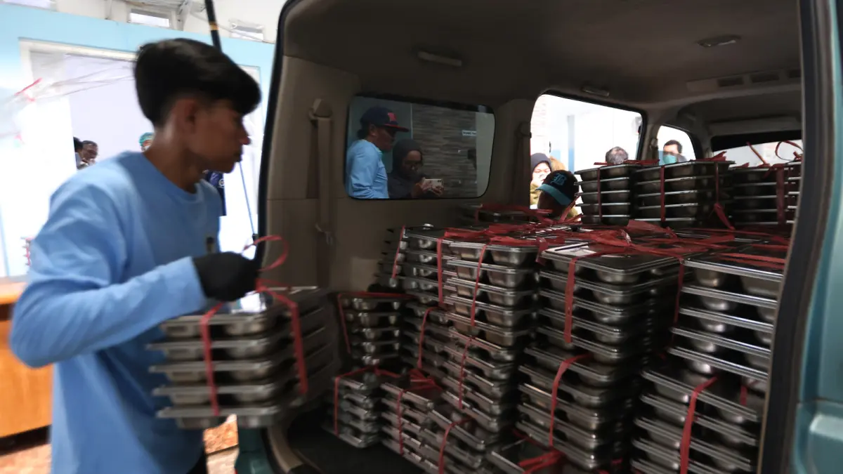 DAPAT SOROTAN: Seorang petugas di salah satu SPPG Kota Malang tengah mendistribusikan MBG ke sekolah, beberapa waktu lalu. Legislatif Kota Malang mendesak perubahan total pelaksanaan program MBG. (Foto: Darmono/Radar Malang)