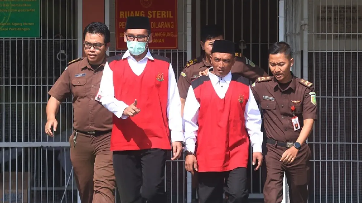 SIDANG KEEMPAT: Terdakwa Agus Muhamad Saleman (pakai masker) dan Suyitno berjalan menuju ruang Sidang Garuda Pengadilan Negeri (PN) Malang Kelas IA, kemarin siang. (Darmono/Radar Malang)