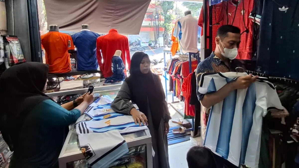 Seorang penggemar sepak bola memilih jersey peserta Piala Dunia 2026 di Arema Sport. (Nabila Amelia/Radar Malang)