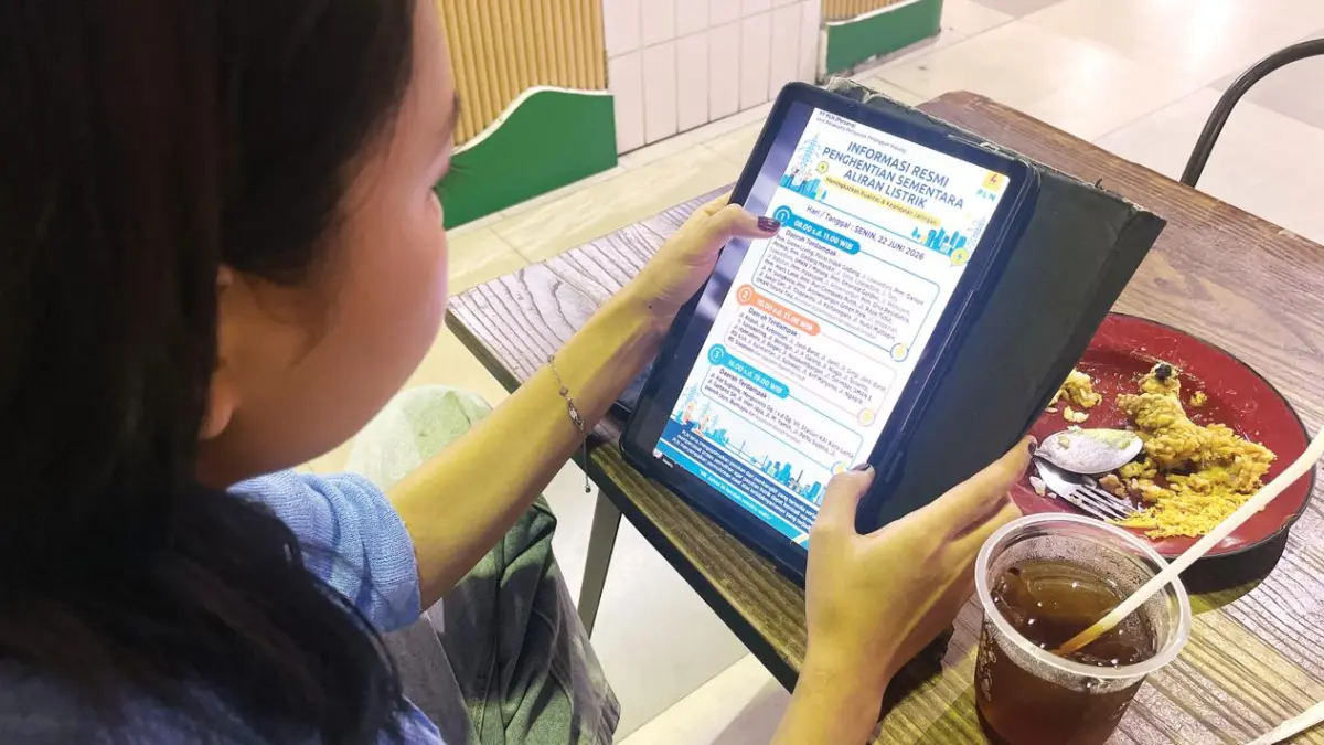 DIBANTAH PLN: Salah satu warga melihat informasi terkait jadwal pemadaman listrik di wilayah Kota Malang yang ternyata hoaks, kemarin. (Nahdiatul Affandiah/Radar Malang)