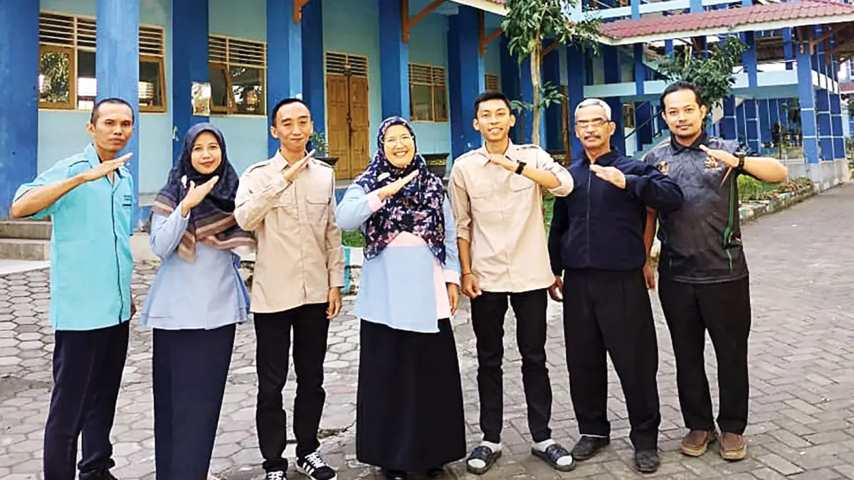 PEMIMPIN BERKUALITAS: Kepala SMK Brantas Karangkates Mintaasih Utami (tengah) didampingi para guru di halaman sekolah.