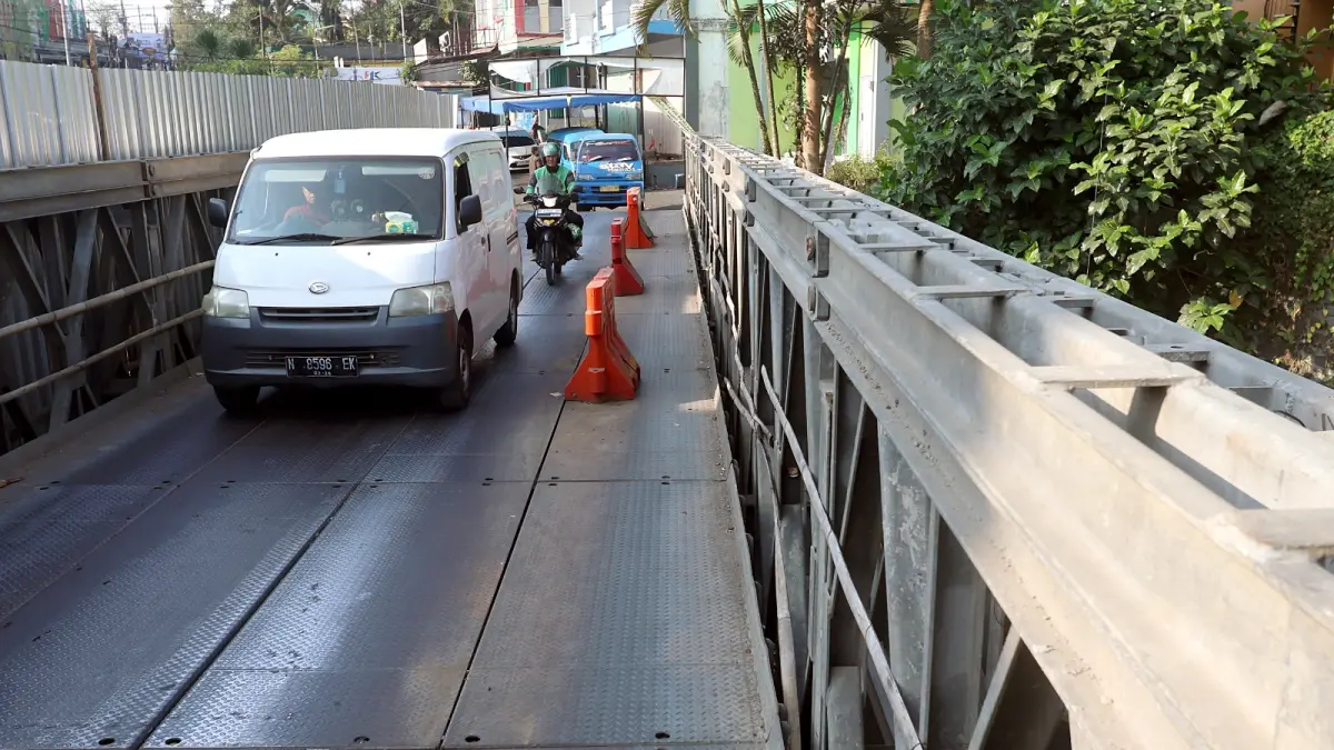 AKSES: Selama pengerjaan berlangsung, kendaraan melintasi jembatan bailey di samping proyek. Jembatan portable itu akan segera dibongkar (DARMONO/RADAR MALANG).