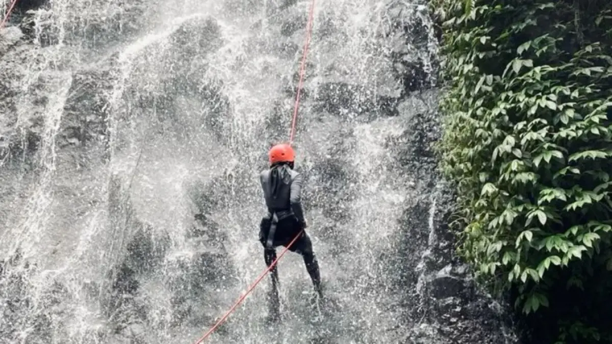 Seorang wanita melakukan olahraga canyoneering di sebuah air terjun. (Sumber: Pinterest/@adindaputri).