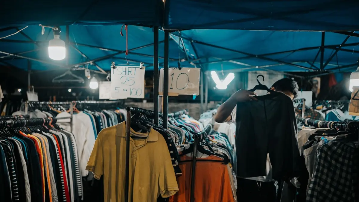 Seseorang memilih baju di pasar barang bekas. (Sumber: Pexels)