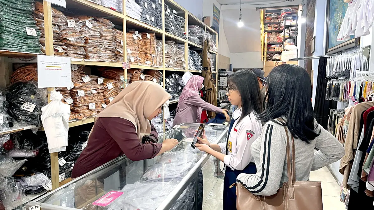 SAMBUT TAHUN AJARAN BARU: Seorang pelajar bersama orang tuanya menunjukkan warna seragam sekolah di salah satu toko di Pasar Besar, kemarin (10/7). (Nahdiatul Affandiah/Radar Malang)