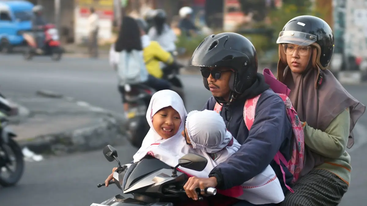 BACK TO SCHOOL: Dua pelajar diantar orang tuanya melintas di Jalan S.Supriadi, Kecamatan Sukun, kemarin. (Darmono/Radar Malang)