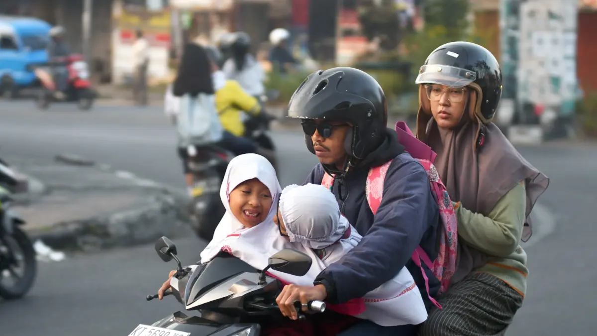 BACK TO SCHOOL: Dua pelajar diantar orang tuanya melintas di Jalan S.Supriadi, Kecamatan Sukun, kemarin.