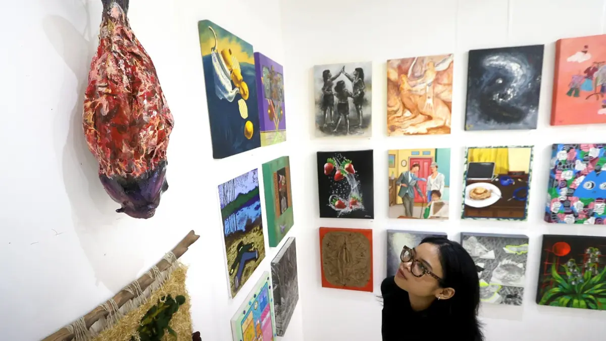 TAHUN KETUJUH: Salah satu pengunjung memperhatikan beberapa karya seniman yang ditampilkan di lantai empat Malang Creative Center (MCC). (Darmono/Radar Malang)