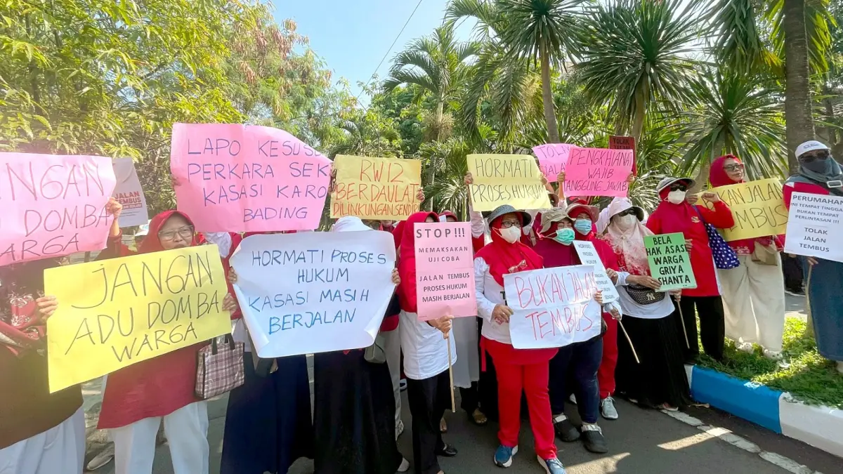 MINTA DITEMUI WALI KOTA: Sejumlah ibu-ibu dari RW 12 Perumahan Griyashanta membentangkan poster berisi penolakan rencana jalan tembus. (Andika Satria Perdana/Radar Malang)