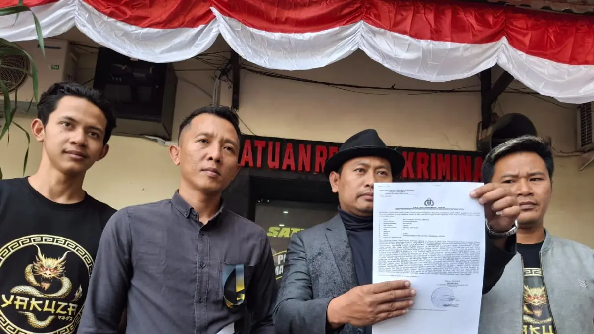 kuasa hukum Yakuza Manages Muhammad Zakki (bertopi) menunjukkan surat laporan polisi. (Nabila Amelia/Radar Malang)