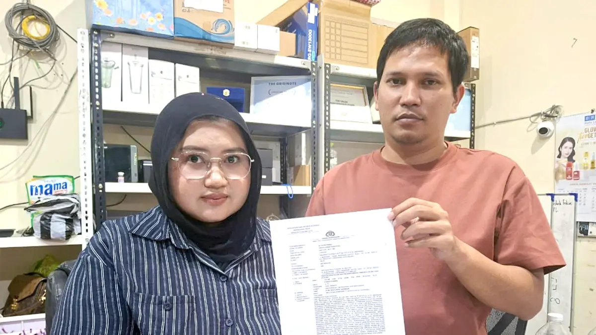 LAPOR SEJAK 2025: Mila Fatma bersama suaminya Taufiq Akbar Romadhoni menunjukkan surat laporan ke Polresta Malang Kota terkait dugaan penggelapan yang dilakukan mantan karyawatinya. (Nabila Amelia/Radar Malang)
