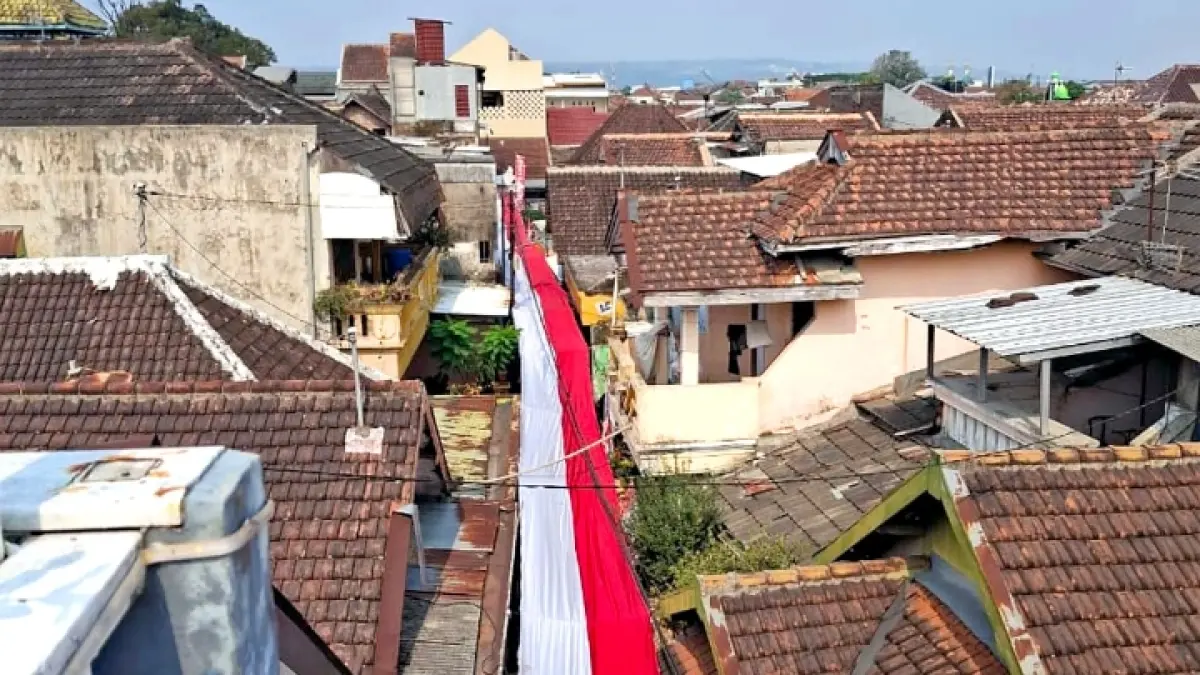 SAMBUT KEMERDEKAAN: Warga RT 5/RW 1 Kelurahan Bareng membentangkan bendera sepanjang 81 meter di gang. (Nabila Amelia/Radar Malang)