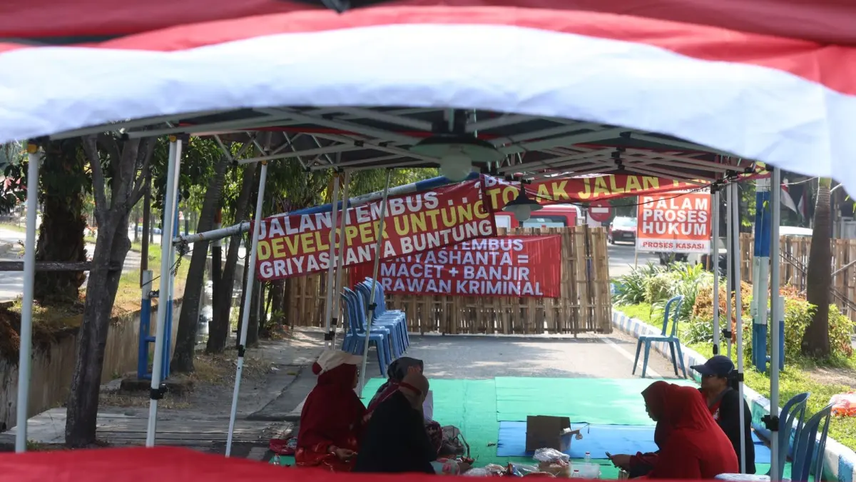 DIJAGA BERGANTIAN: Warga Perumahan Griyashanta mendirikan tenda di depan blokade non-permanen yang sudah ada sejak 27 Juli lalu. (Darmono/Radar Malang) 