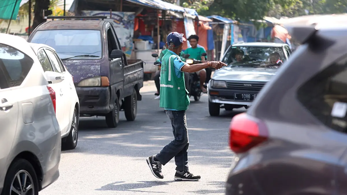 DISOROT DEWAN: Salah satu jukir memberi aba-aba untuk pengendara di Jalan Ade Irma Suryani, Klojen, kemarin (7/8). &nbsp;