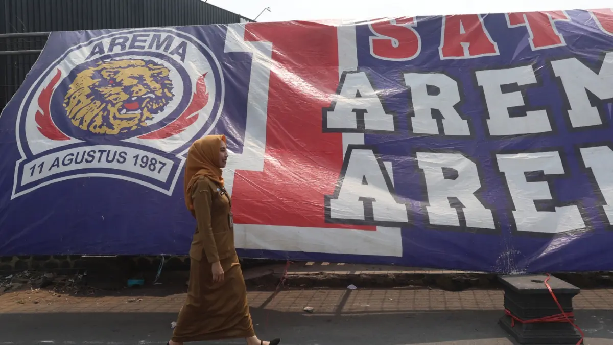 EUFORIA: Staf Prokoppim Pemkot Safira melintas di Jembatan Ngaglik Kecamatan Sukun. Pemkot mengeluarkan surat edaran untuk ASN mengenakan atribut Arema hari ini (11/08). (Foto: Darmono)