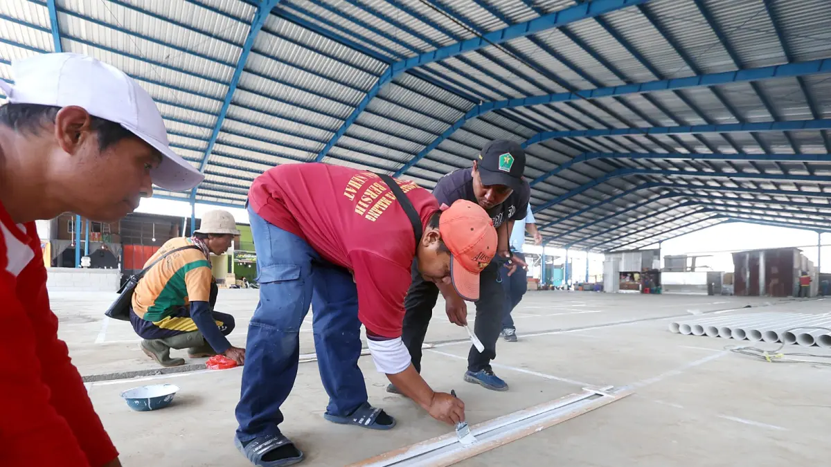 SIAP-SIAP PINDAH: Sejumlah petugas mengecat batas lapak di tempat relokasi kedua Pasar Gadang, kemarin. Setelah itu diskopindag bakal memberi nomor untuk setiap lapak. Foto: Darmono/Radar Malang