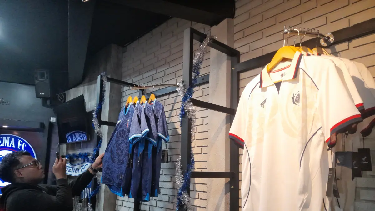 Seorang pengunjung Arema FC Store melihat detail jersey Arema FC. (M. Affan Fauzan/Radar Malang)