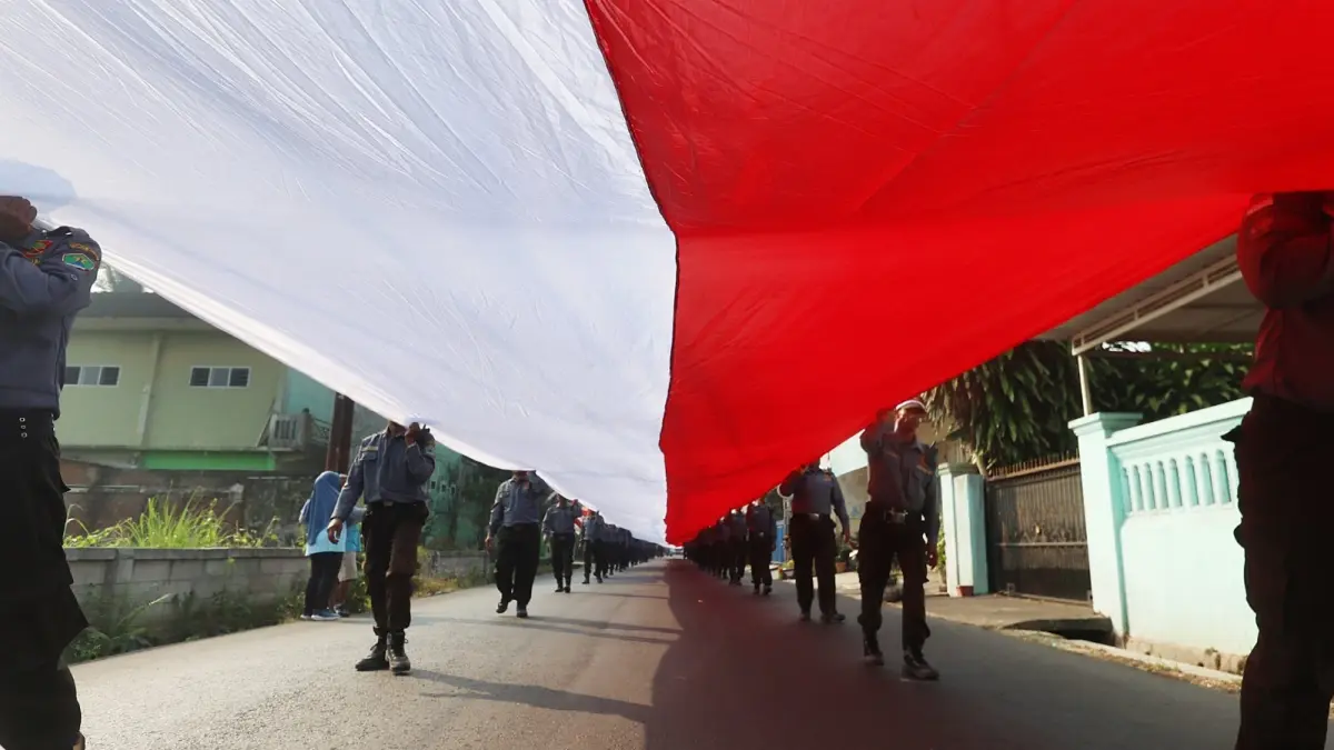 AGENDA TAHUNAN: Kirab bendera merah putih sepanjang 81 meter dilakukan puluhan anggota Linmas bersama warga Kelurahan Bumiayu, kemarin. (Darmono/Radar Malang)