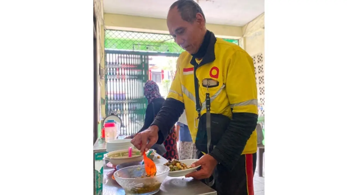 BERBAGI MANFAAT: Seorang pengemudi ojek online mengambil makanan gratis yang disediakan Griyo Dahar Sarikat Buruh Muslimin Indonesia (Sarbumusi) Kota Batu.