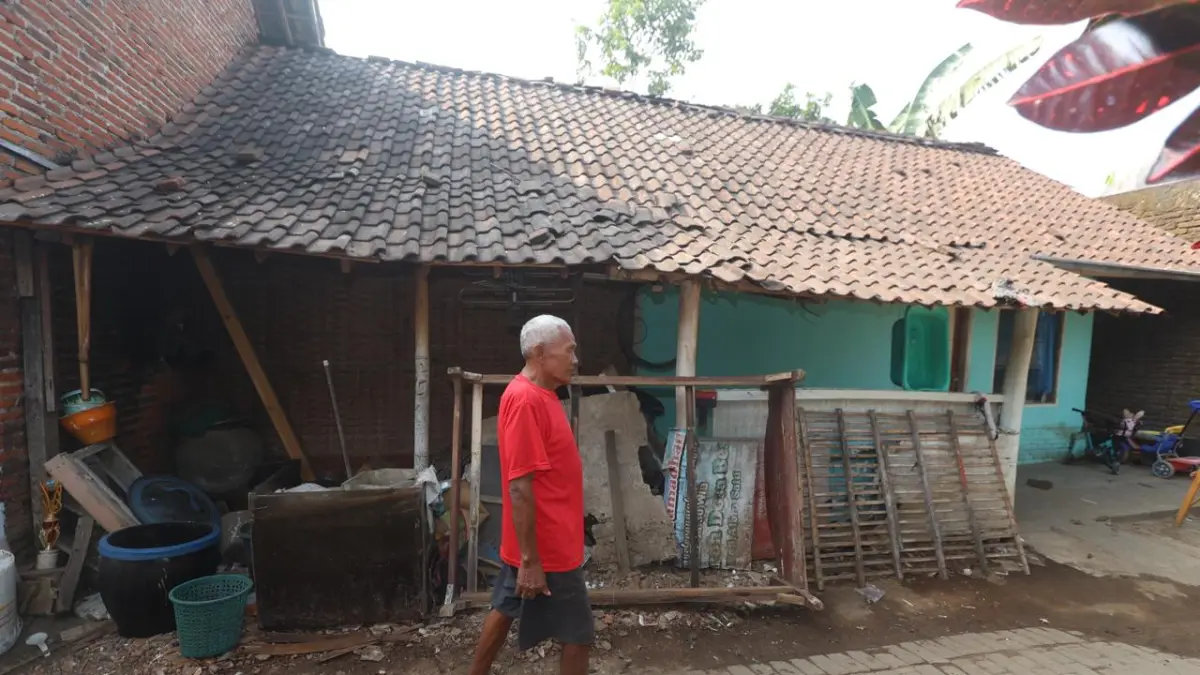 BUTUH PERHATIAN: Seorang warga Jalan Binangun Dalam, Desa Genengan, Kecamatan Pakisaji bersantai di depan rumahnya yang berdinding anyaman bambu.