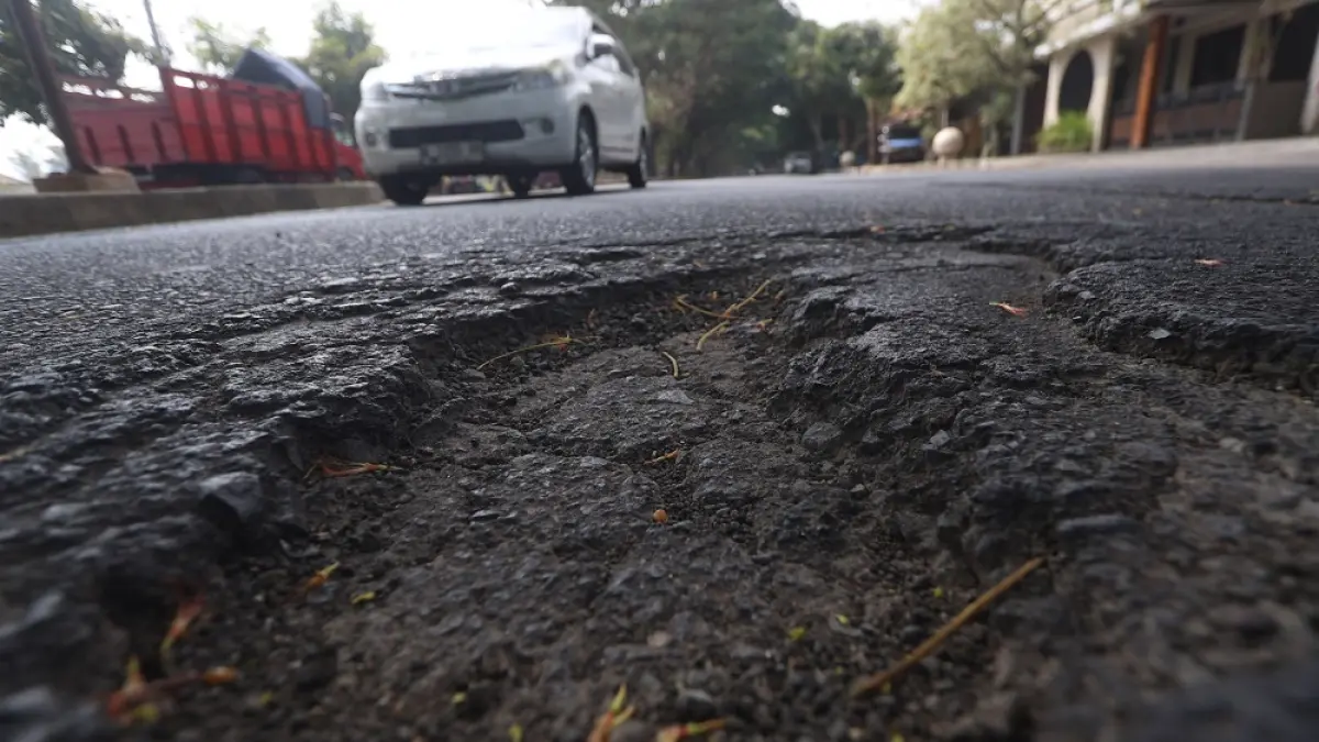 Mobil melintasi jalan berlubang di Jalan Rajasa Malang (Darmono/Radar Malang)