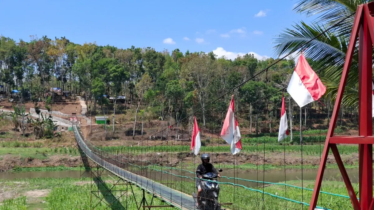 Pengendara motor melintasi jembatan gantung yang goyang