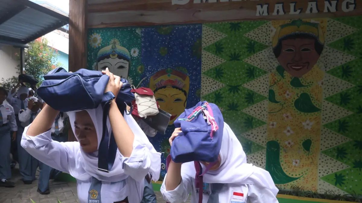 BELAJAR MITIGASI BENCANA: Siswi SMK Negeri 7 Kota Malang melakukan simulasi menyelamatkan diri menuju titik kumpul yang aman pada waktu terjadi gempa bumi, kemarin. (Darmono/Radar Malang)