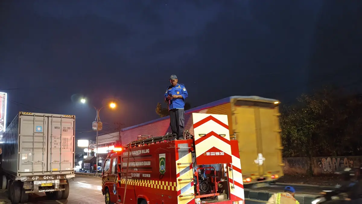 Personel damkar Kabupaten Malang membersihkan ruas jalan