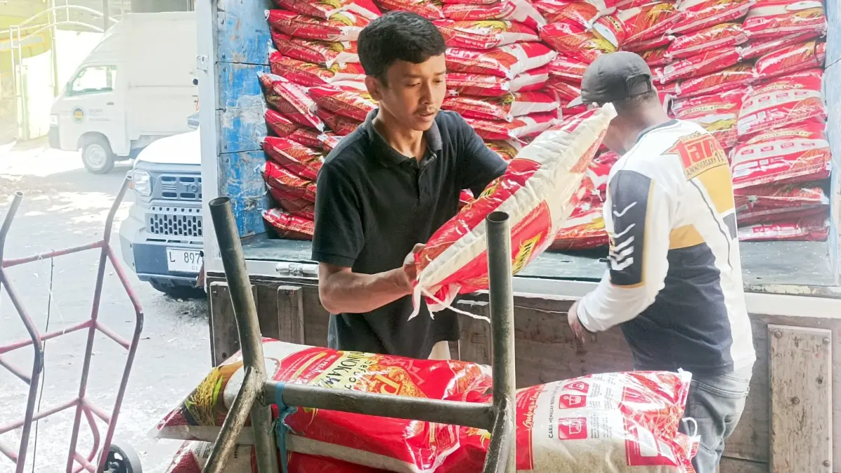BANTU DROPPING: Tim dari Bulog Malang menurunkan ratusan sak beras premium jenis baru untuk didistribusikan di Pasar Bunulrejo, kemarin (18/9). (Nabila Amelia/Radar Malang)