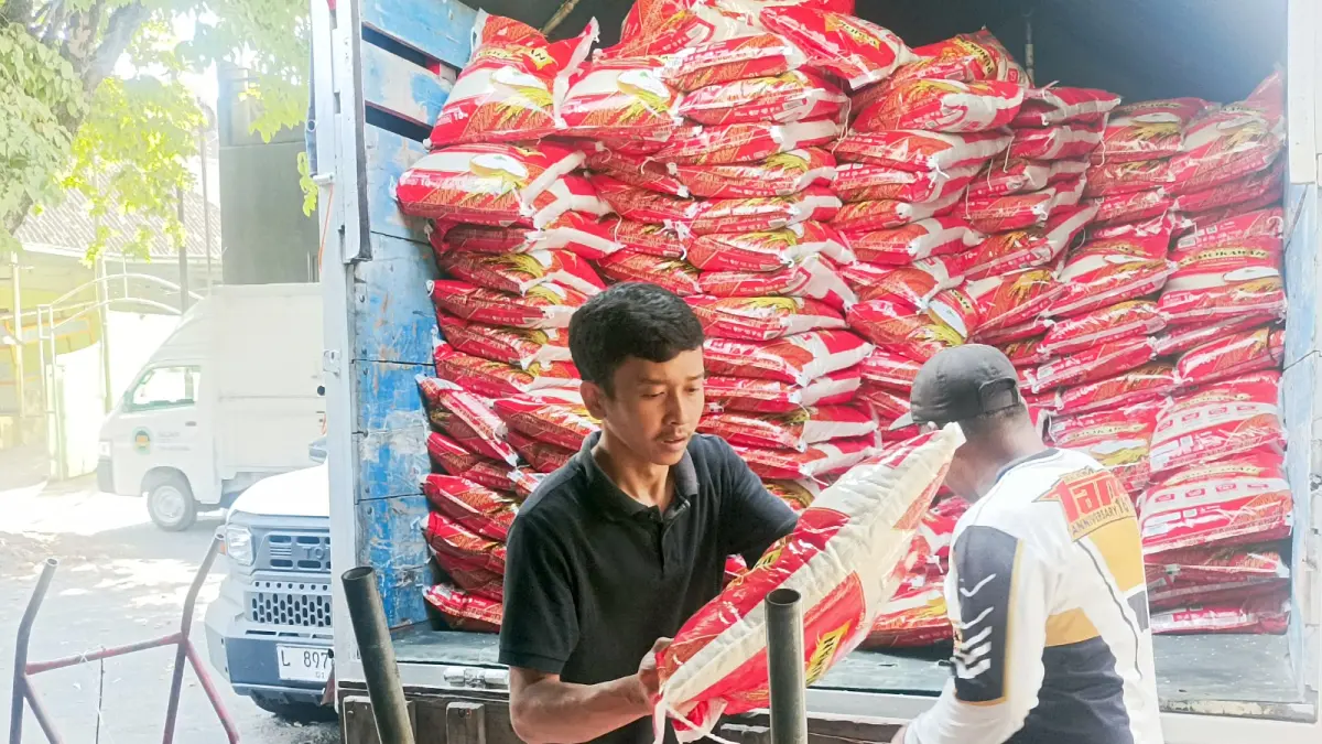 BANTU DROPPING: Tim dari Bulog Malang menurunkan ratusan sak beras premium jenis baru untuk didistribusikan di Pasar Bunulrejo, kemarin (18/9).