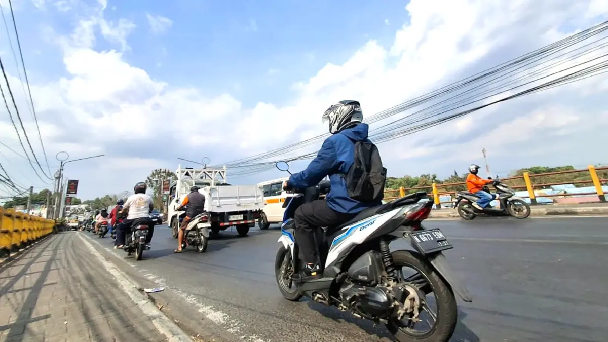 MENYENGAT: Cuaca yang lebih terik dirasakan pengguna jalan yang melintas di Jembatan Brantas, kemarin (7/10). (Nabila Amelia/Radar Malang)
