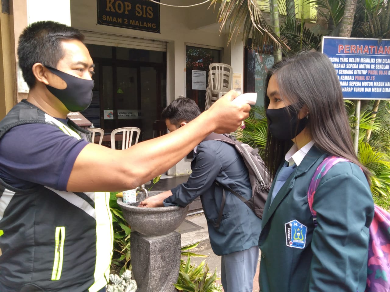Siswi SMAN 2 Malang dicek suhu tubuhnya sebelum masuk sekolah. Foto: Imam Nasrodin/Radar Malang