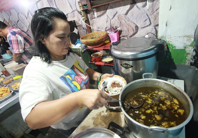 RACIKAN KHAS: Nita Yuliana, istri dari pemilik warung Rawon Disco mengambilkan seporsi rawon untuk pelanggan warungnya. (Foto: Laoh Mahfud/Radar Malang)