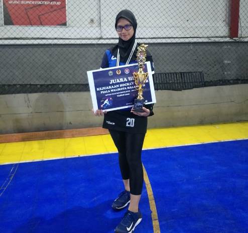 Viqa Velvi Abrika menenteng piala dan piagam kejuaraan hockey. (Viqa Velvi Abrika for Radar Malang)