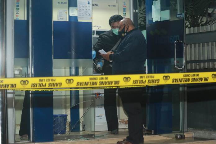 RUSAK: Pintu kaca ATM Bank Mandiri di Jalan Kawi yang mengalami kerusakan setelah ditembak oleh seseorang, Senin (31/8) malam, sekitar pukul 21.45 WIB. (Foto: Laoh Mahfud/Radar Malang)