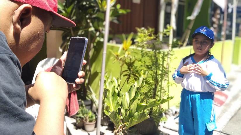 SAYANG ANAK: Riki Putra (pegang HP) saat mendampingi buah hati praktik mapel PJOK. (Foto: Imam Nasrodin/ Radar Malang)