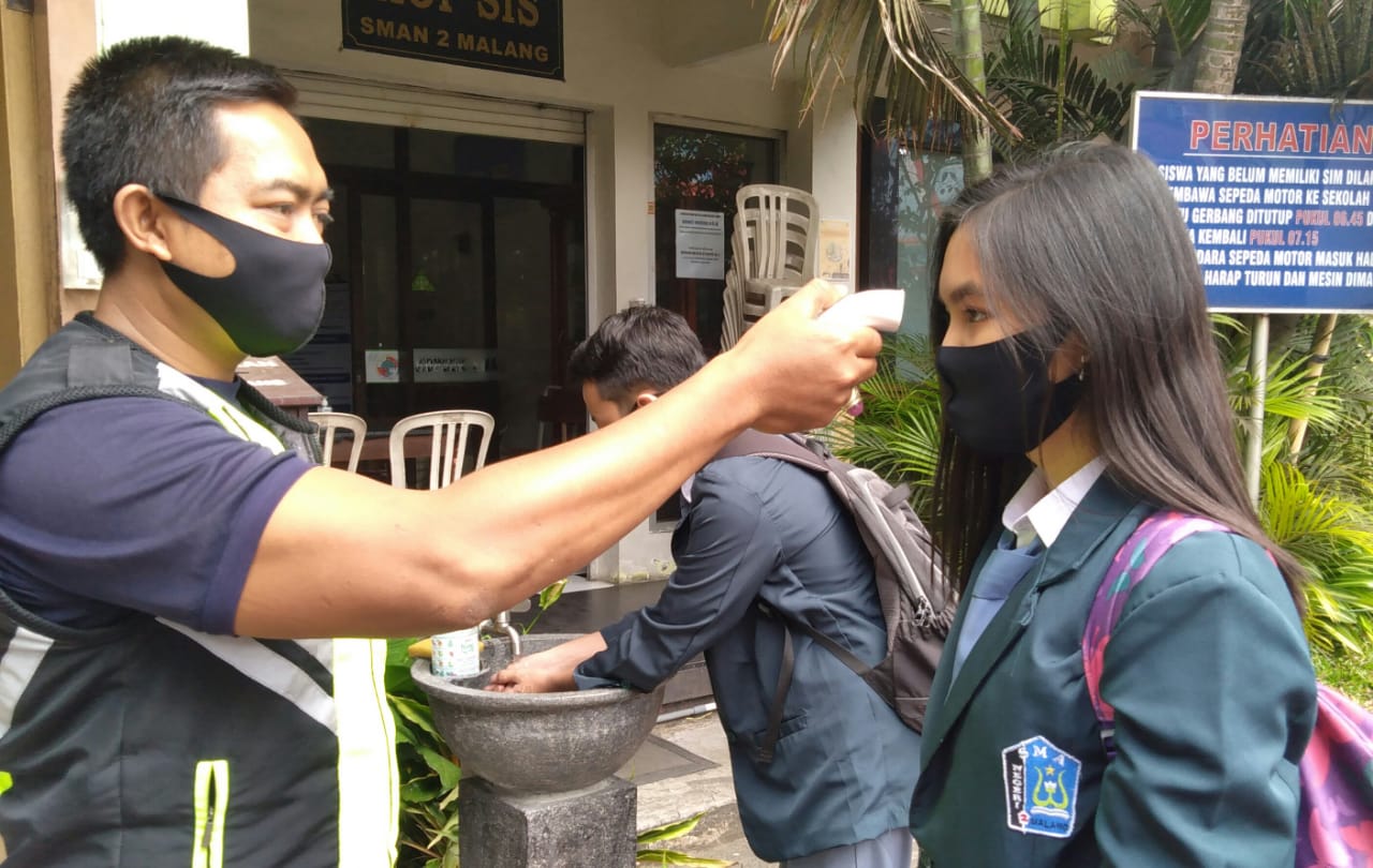 Salah satu siswa SMAN 2 Kota Malang menjalani cek suhu di pintu gerbang sekolah. (Imam N / Radar Malang)