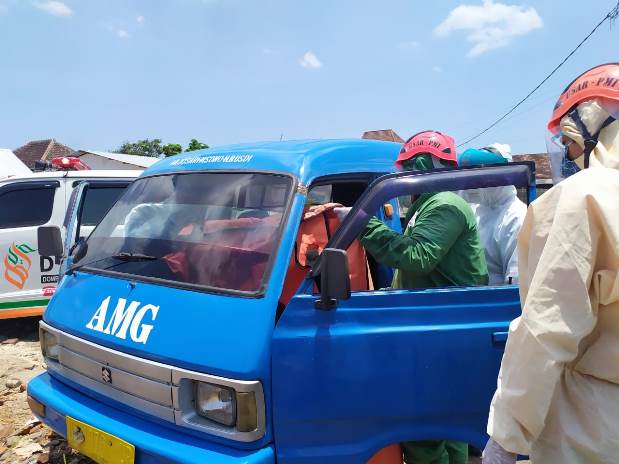 Petugas dengan pakaian protokol lengkap mengevakuasi jenazah pengemudi angkot jalur AMG yang meninggal di dalam angkot yang dikendarainya. (Biyan Mudzaky Hanindito/Radar Malang)