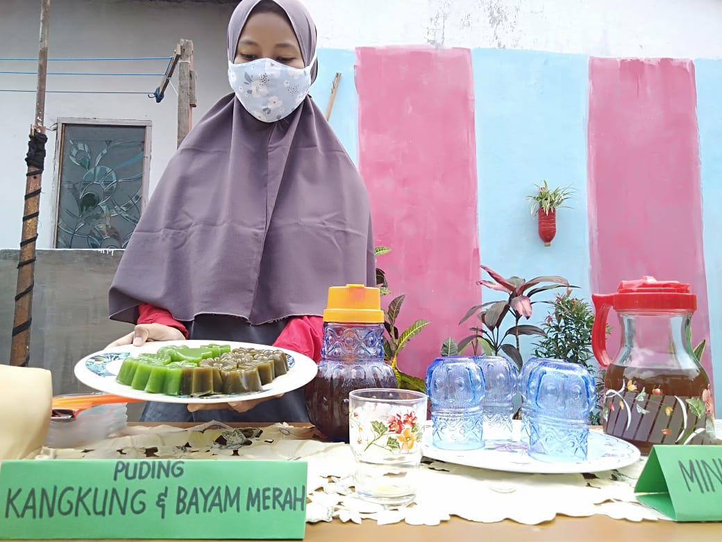 Warga RW 02 Tanjungrejo, menunjukkan hasil olahan puding bayam dan kangkung.  (Imam Nasrodin/Radar Malang)