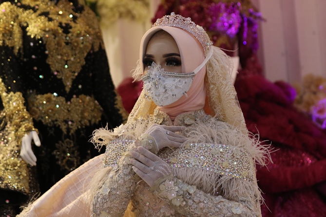 Salah seorang model mengenakan busana pengantin lengkap dengan masker saat pameran di MOG. (Darmono/Radar Malang)