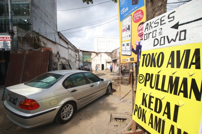 Pengguna jalan memanfaatkan jalur tembusan dari tembok belakan Toko Avia di Jalan Basuki Rahmat yang dijebol untuk akses warga ke kawasan Kayutangan. (Laoh Mafud/Radar Malang)