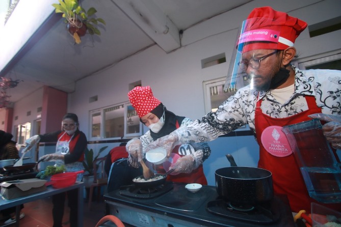 Aksi para tenaga pendidik SMK Prajnaparamita mengikuti lomba memasak untuk merayakan Hari Guru, di Rayz Hotel UMM, Rabu (25/11). (Laoh Mahfud/Radar Malang)