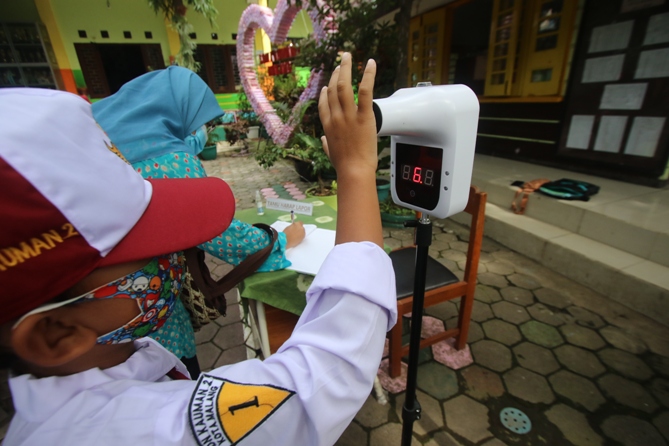 Salah satu siswa SDN Kauman 2 menerapkan protokol kesehatan saat masuk (DARMONO/ RADAR MALANG)