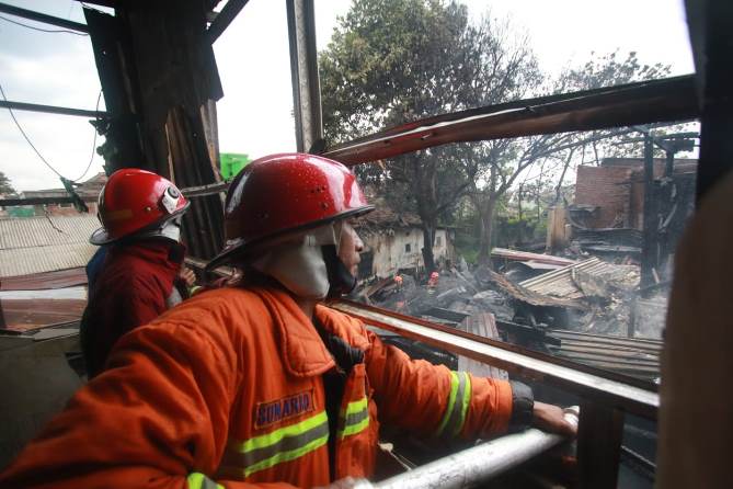 Petugas pemadam kebakaran tengah berusaha memadamkan sumber api di salah satu lokasi kebaran di Kota Malang. (Laoh Mahfud/Radar Malang)