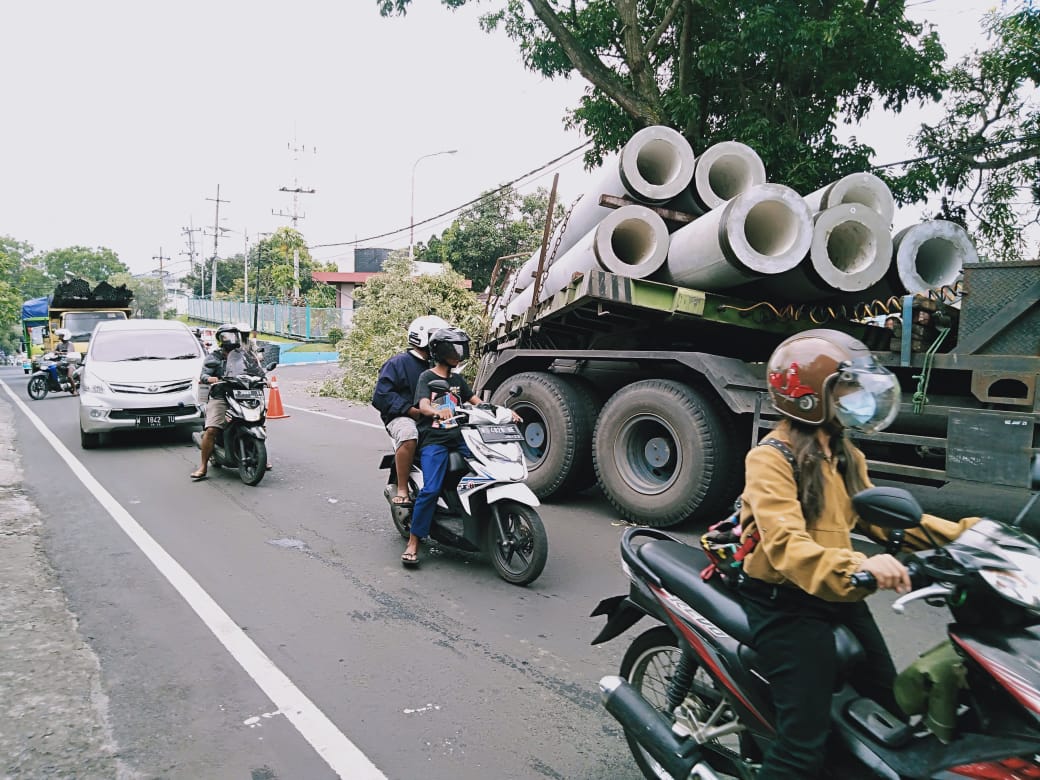 badan truk kontainer yang memakan sebagian badan jalan membuat pengguna jalan harus lewat bergantian. (Imam N / Radar Malang)