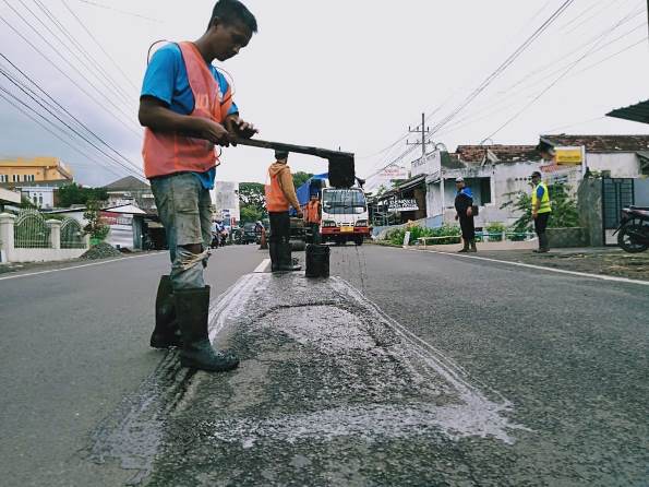 Petugas DPUPR Kota Batu melakukan penambalan jalan berlubang di sepanjang Jalan Soekarno-Hatta (Soehat), Kamis (17/12). (Imam Nasrodin/Radar Malang)