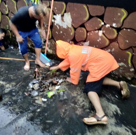 Petugas dari BPBD Kota Malang dibantu warga membersihkan sampah yang menutupi jalan air, Jumat (25/12). (Humas Pemkot Malang for Radar Malang)