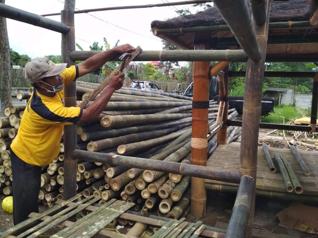 Asmad sedang menyelesaikan pengerjaan gazebo berbahan bambu. (Wildan Agta / Radar Malang)