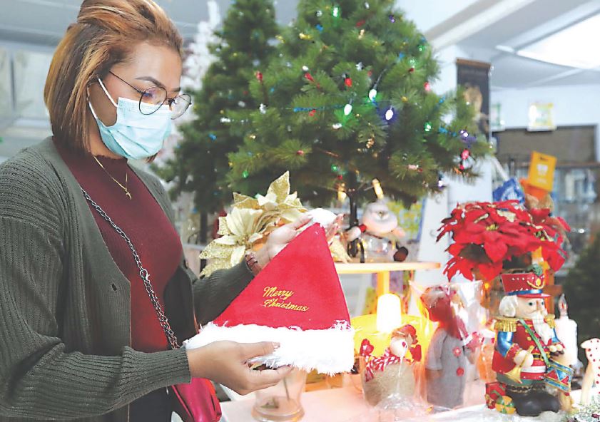 Salah seorang pelanggan memilih pernak-pernik natal di toko Dioma, Jalan Kawi, Kota Malang. (Rubianto/Radar Malang)