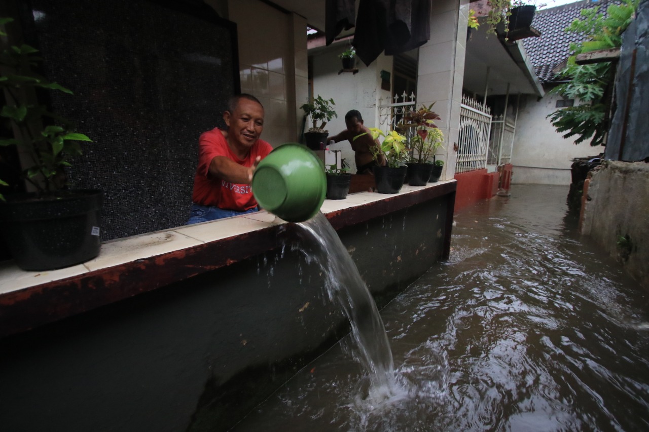 Warga Jalan Ir Rais Gang II, Bareng, Kota Malang menguras air di teras rumah setelah kebanjiran. (Laoh Mahfud / Radar Malang)